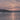 Närbild av solnedgång över frusen sjö med skogsklädd strand och snö. Frostlit Farewell